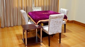 A room with a wooden floor, a bed with a purple bedspread, two upholstered chairs, and a small table. - Peigen Yizutang Hotel (Huizhou)