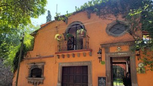 A building with a brown door, a balcony with plants, and a sign for "Tres Fuentes Hotel & Boutique." - Tres Fuentes Hotel Boutique (San Miguel de Allende)
