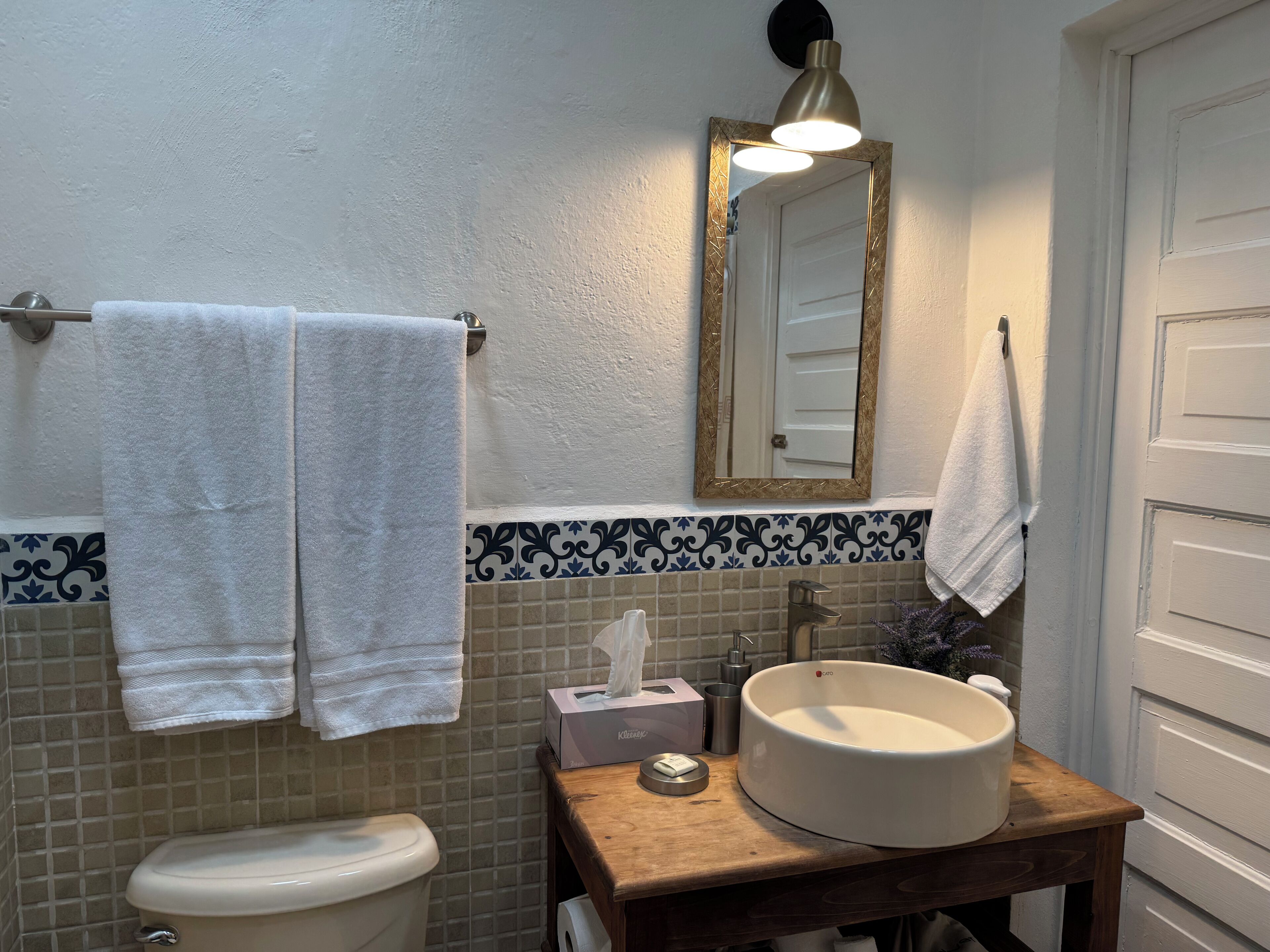 A bathroom with a toilet, sink, mirror, and towels.