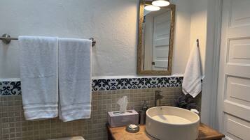 A bathroom with a toilet, sink, mirror, and towels.