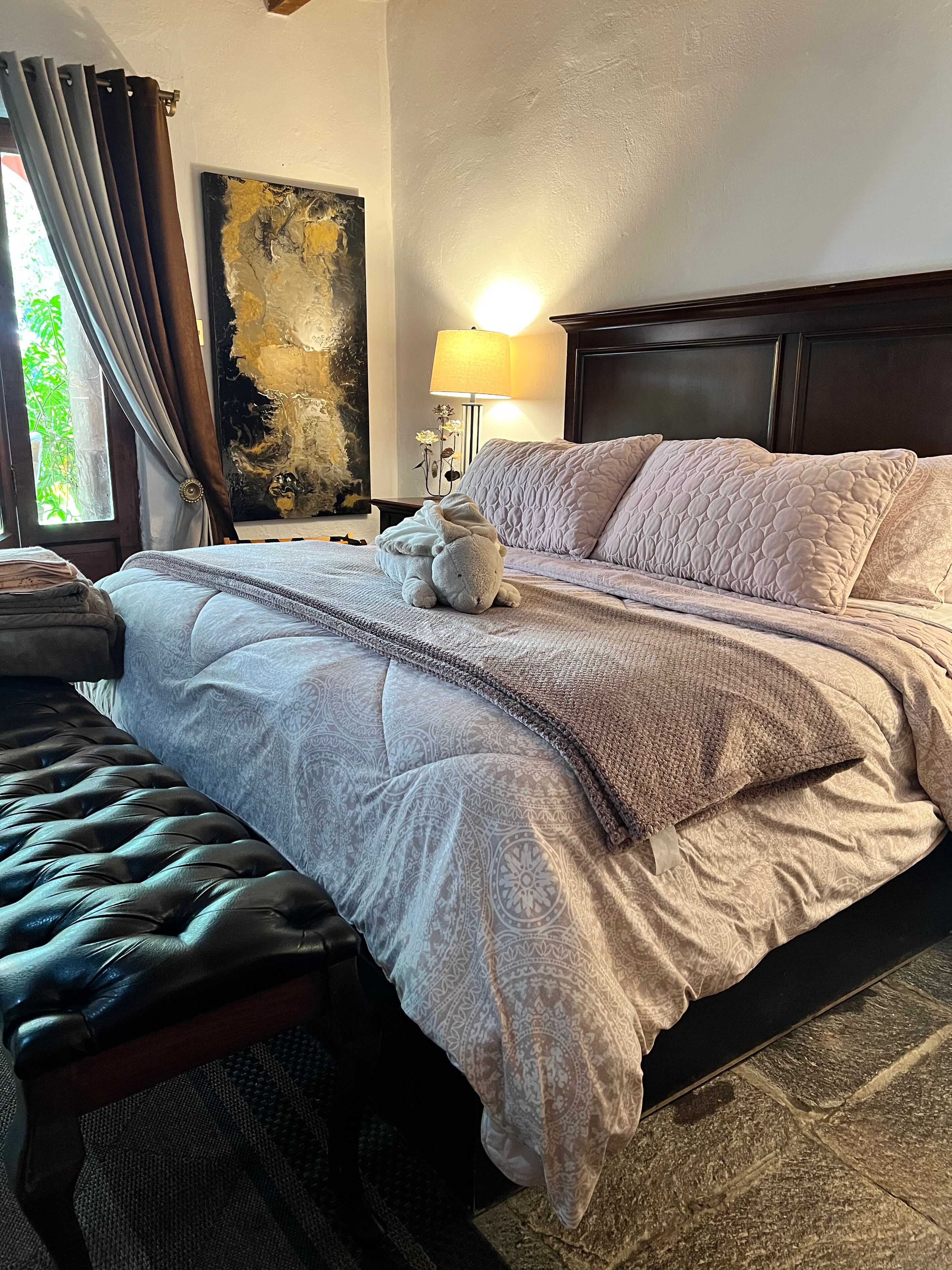A neatly made bed with a quilted blanket, a bedside lamp, and a decorative pillow.