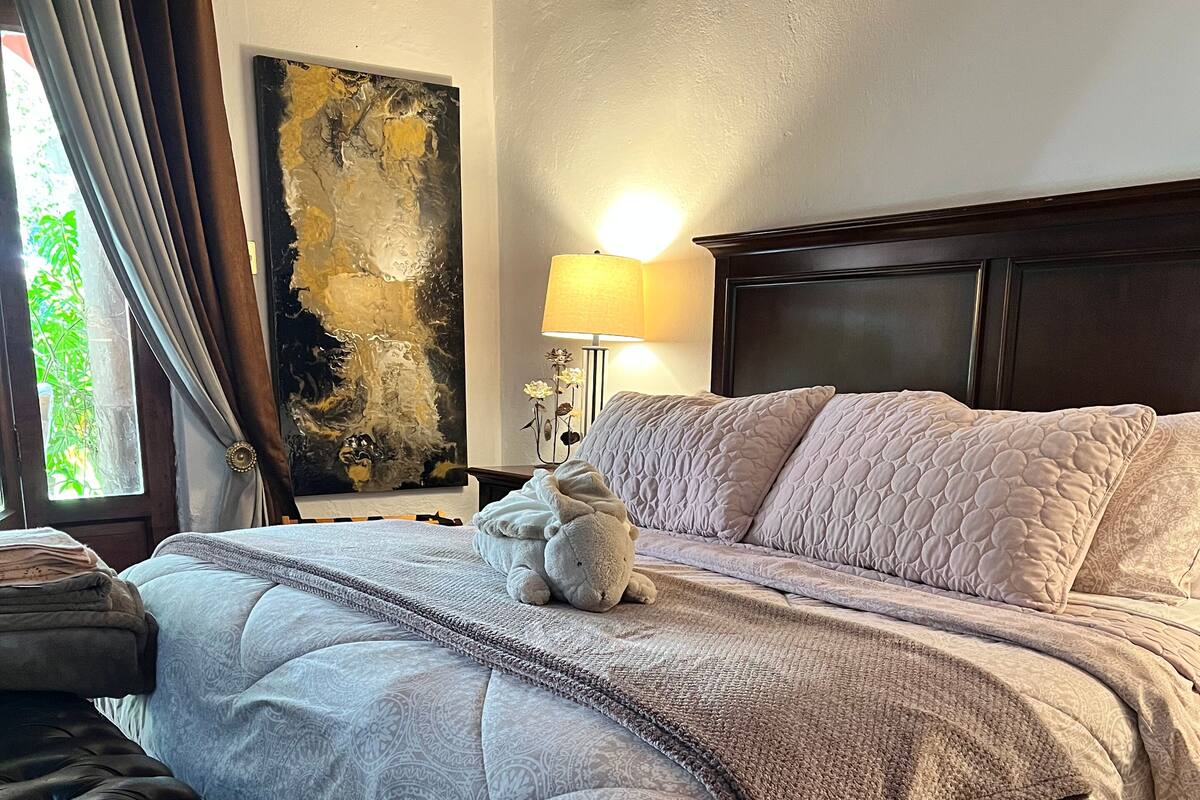 A neatly made bed with a quilted blanket, a bedside lamp, and a decorative pillow.