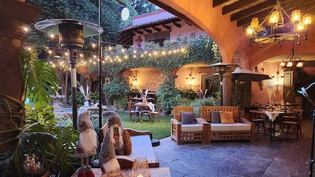 An outdoor patio area with rustic furniture, string lights, and decorative elements. - Tres Fuentes Hotel Boutique (San Miguel de Allende)