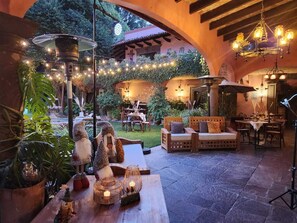 An outdoor patio area with rustic furniture, string lights, and decorative elements. - Tres Fuentes Hotel Boutique (San Miguel de Allende)