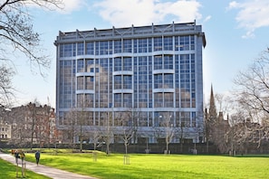 Stunning building with curved windows and a flat roof, set amidst a serene grassy area with a pathway.