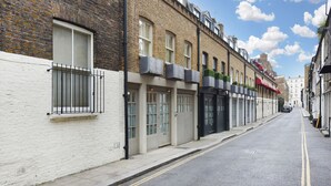 Une rue étroite bordée de bâtiments traditionnels en briques, avec des portes et des fenêtres de style uniforme, et un ciel dégagé au-dessus.