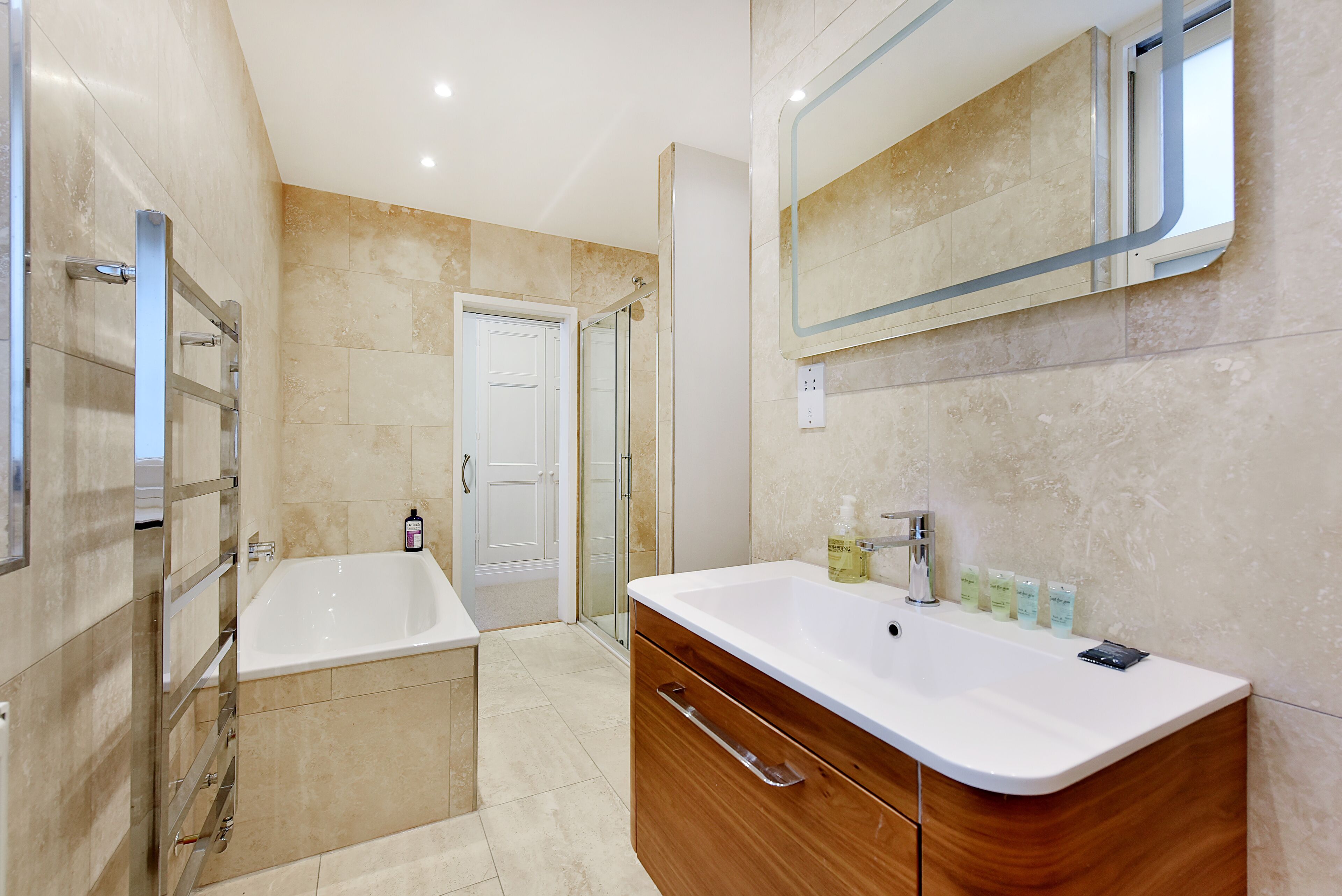 A modern bathroom with a bathtub, vanity, and a glass shower enclosure.