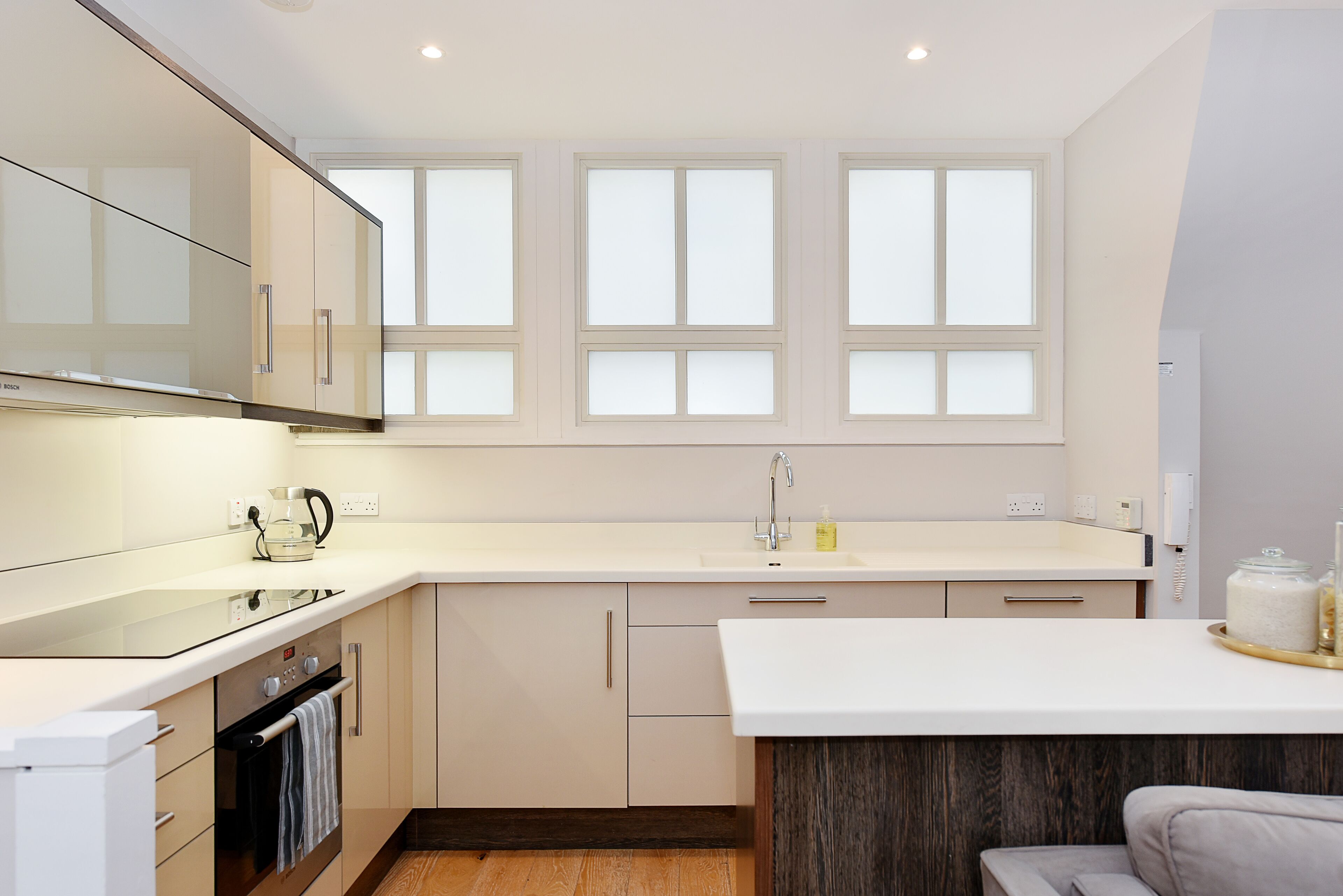 Una cocina moderna con una isla grande, horno empotrado y una ventana con vidrios esmerilados.