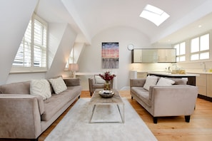 Relax in this stylish living space with a loft-style ceiling, featuring a neutral color palette and a large window.
