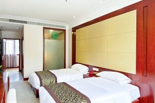 A hotel room with two beds, a wooden headboard, a mirror, and a door with a frosted glass panel.