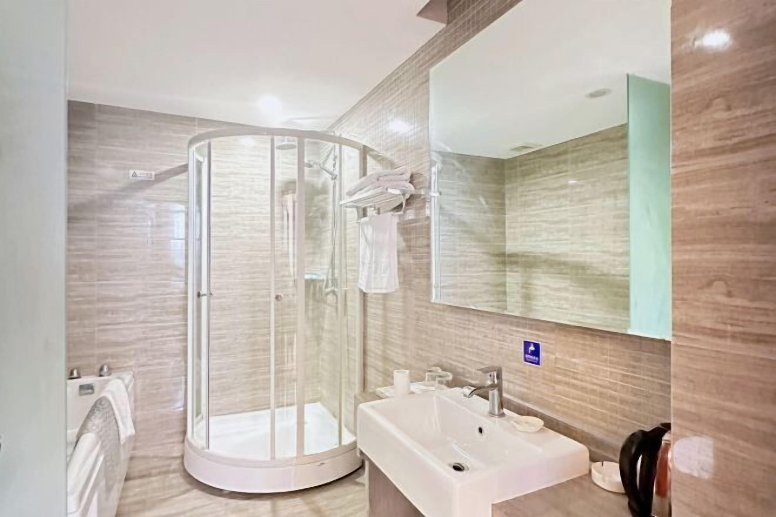 A modern bathroom with a glass-enclosed shower, a sink, and a mirror.