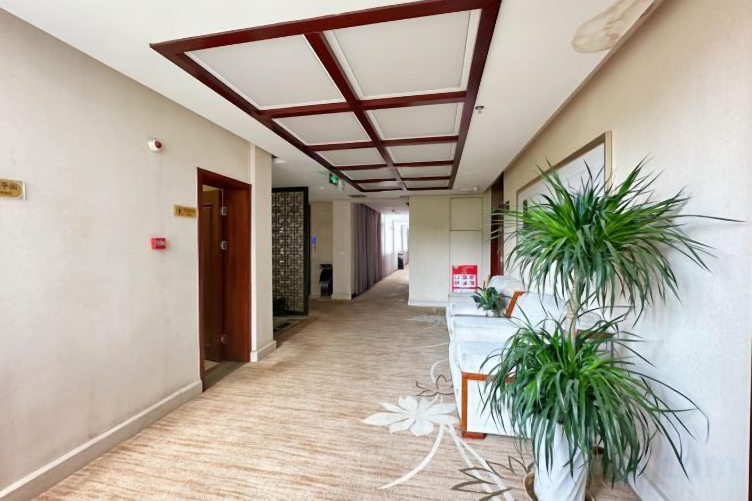 A hotel corridor with a reception desk, a reception area, and a door on the left.
