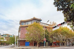 Un edificio con entrada en esquina, escaparate visible y un semáforo.