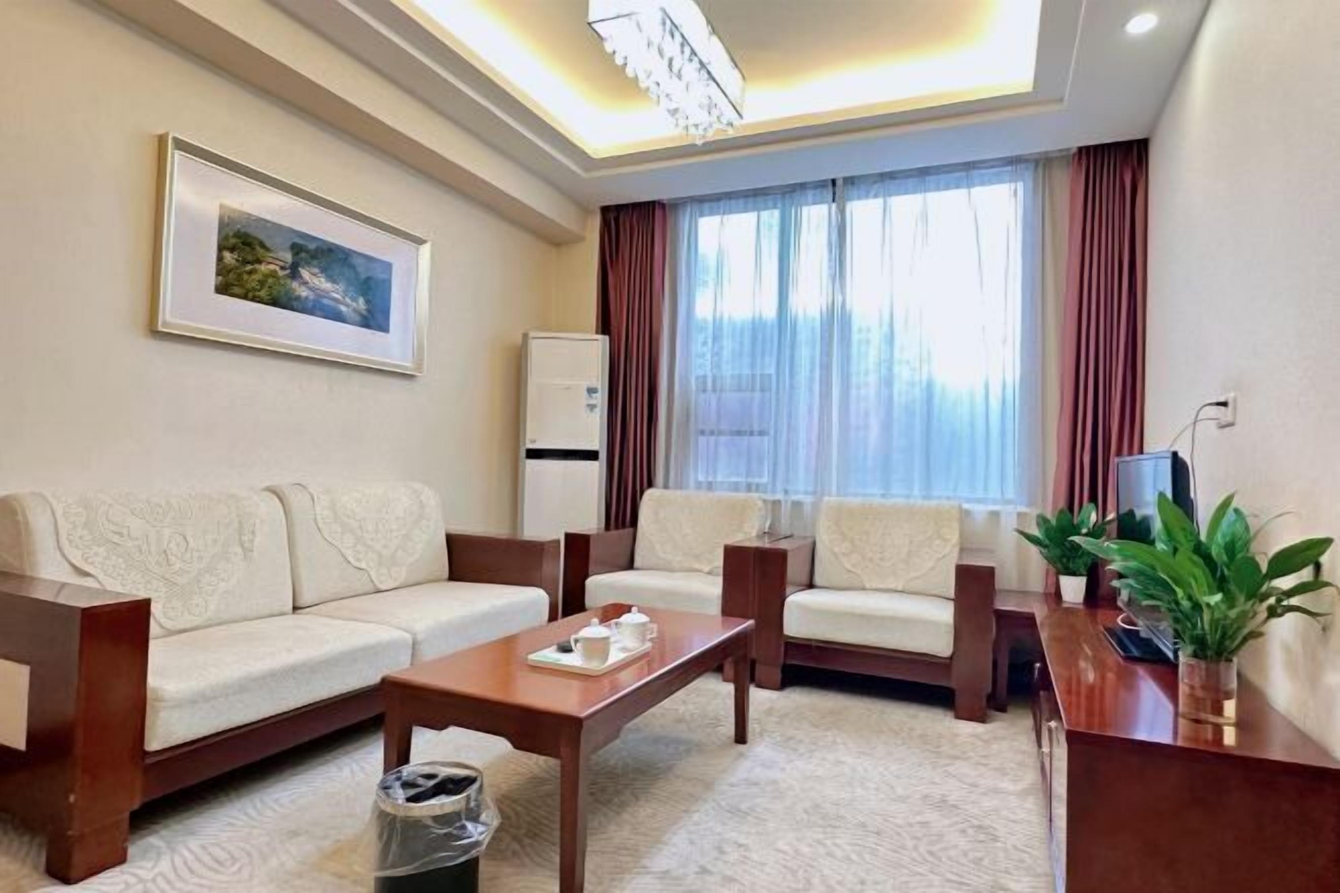 Una habitación de hotel con un conjunto de sofás, una mesa de centro, un televisor y un cuadro en la pared.