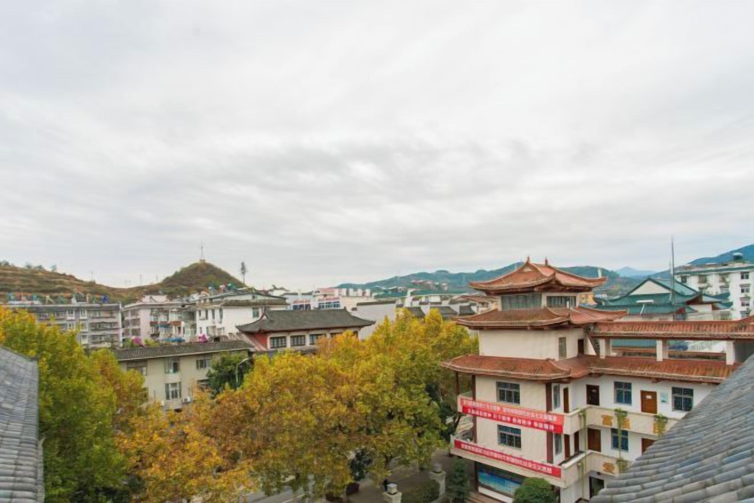 A town with traditional architecture, including a pagoda-style building and a hill in the background.