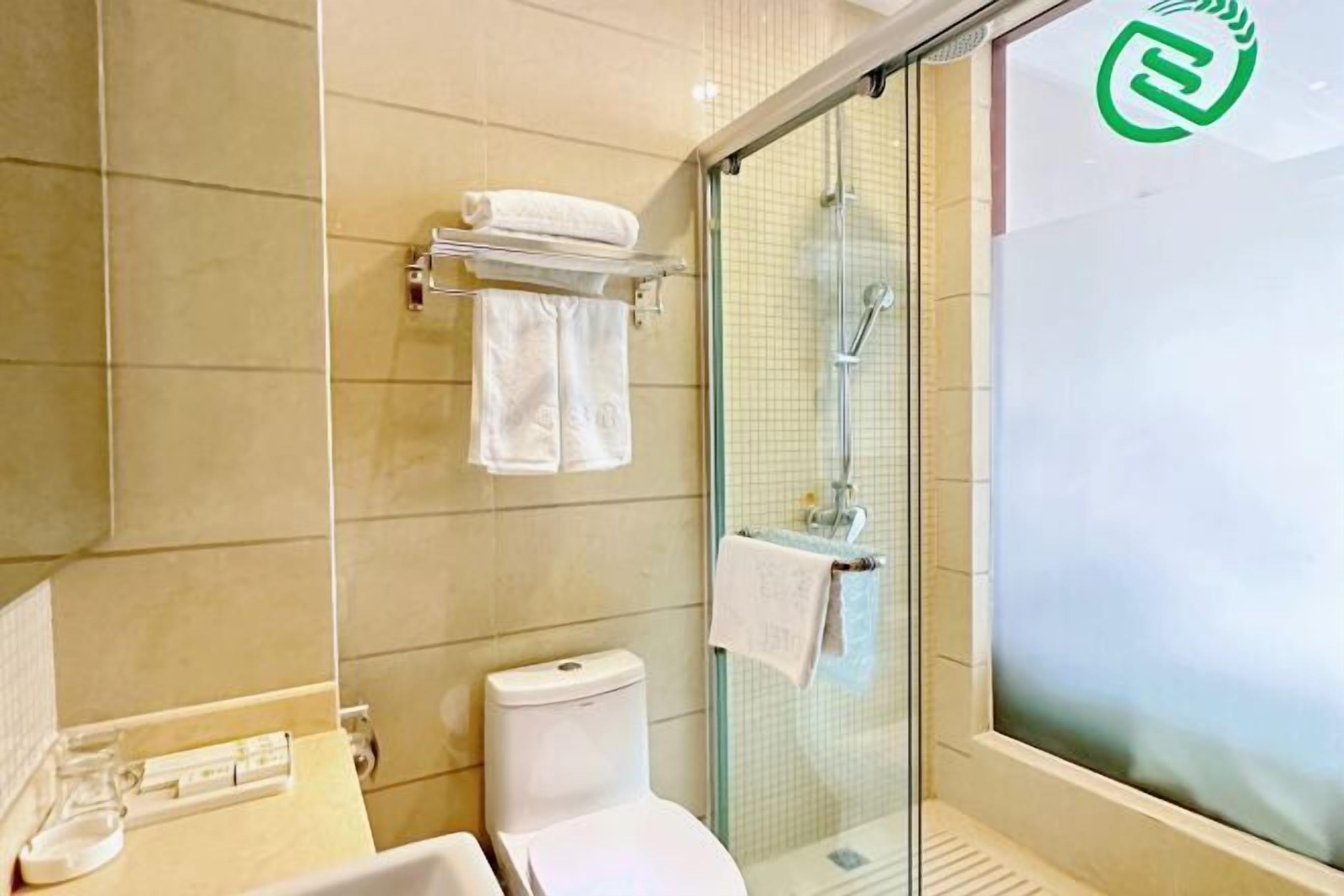 Une salle de bain avec une douche à parois de verre, des toilettes et un lavabo équipé d’un porte-serviettes.