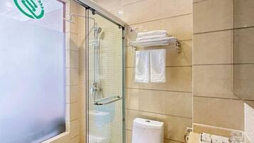 A bathroom with a glass shower enclosure, a toilet, and a towel rack with folded towels.