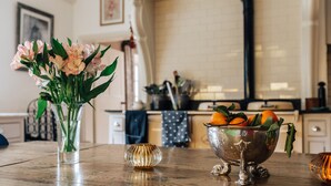 A kitchen counter with a vase of flowers, a bowl of oranges, and a decorative glass bowl. - Georgian Old Rectory with heated Pool
82  5 Star Reviews on Trip Advisor (Maidford, Towcester)