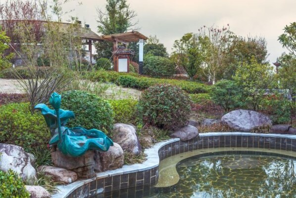 A landscaped garden with a pond, rocks, and a sculpture. - Tangxi Hot Spring Resort (Chongren)