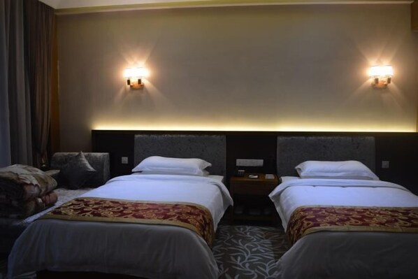 A hotel room with two beds, a headboard with integrated lighting, a nightstand, and a patterned carpet.