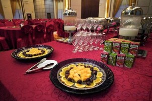 Una mesa de banquete con platos de comida, vasos y dispensadores de bebida.