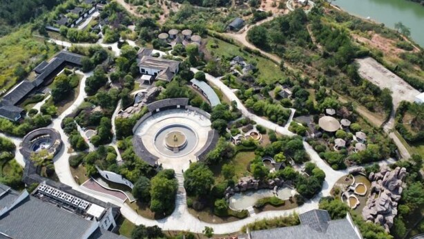 An aerial view of a landscaped area with a central circular fountain, surrounded by pathways and greenery. - Tangxi Hot Spring Resort (Chongren)