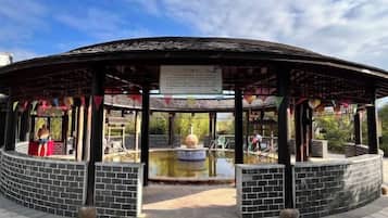 A pavilion with a tiled floor, a central fountain, and a covered seating area.