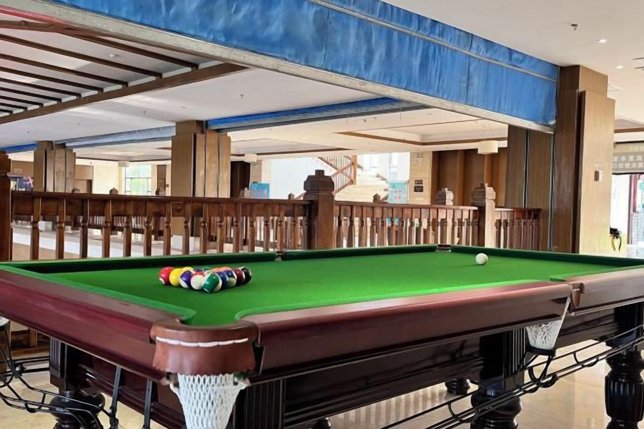 A pool table with balls, a wooden railing, and a view of a staircase.