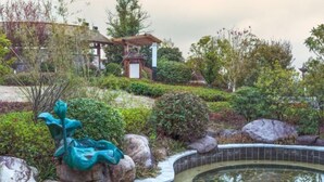 A landscaped garden with a pond, rocks, and a gazebo. - Tangxi Hot Spring Resort (Chongren)