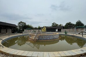 A circular pool with a central fountain, surrounded by a stone deck. - Tangxi Hot Spring Resort (Chongren)
