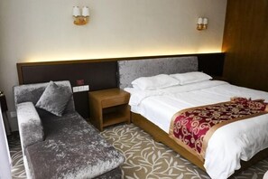 A hotel room with a bed, a sofa, a nightstand, and wall-mounted lamps.