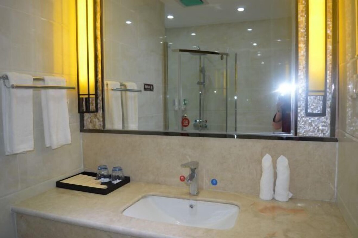 A bathroom with a sink, mirror, and shower.
