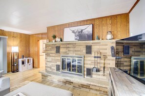 A living room with a fireplace, wooden paneling, and a mounted picture of a bull. - Cozy Wisconsin Abode: Walk to Lake Michigan! (Algoma)