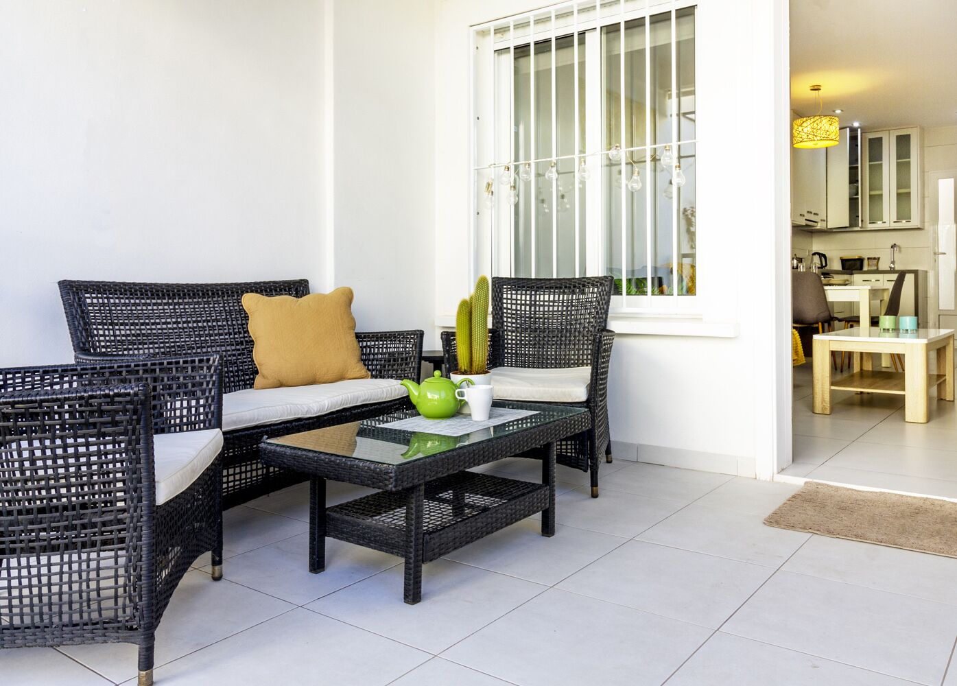 A modern living area with wicker furniture, a glass coffee table, and a cactus plant.
