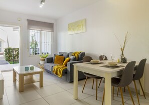 Uma sala de estar moderna com um sofá, uma mesa de jantar com cadeiras e uma pequena mesa de centro.