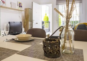 A dining area with a table set for two, a television, and a view of the outdoors. - Apartment Pink Vistabella 1 (Torrevieja)