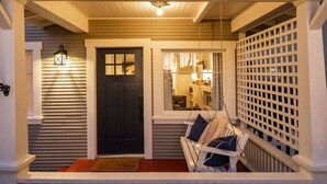 A porch with a swing, a door, and a window with a view into the house. - The Birdhouse at The Birdbath Bungalows (Ventura)