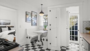 A compact kitchen with a checkered floor, a dining table, and a stove. - The Birdhouse at The Birdbath Bungalows (Ventura)