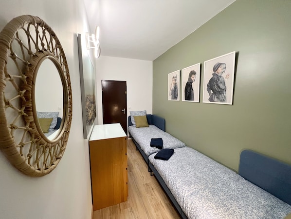 A room with a bed, a wooden dresser, a mirror, and three framed pictures on the wall.