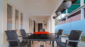 A conference room with a black table and six chairs, large windows, and a view of a blue building. - Royal Vista (Jorhat)