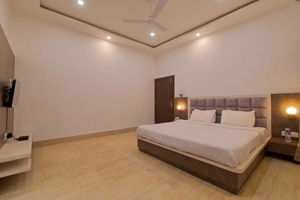 A modern bedroom with a bed, a ceiling fan, recessed lighting, and a nightstand with a lamp.
