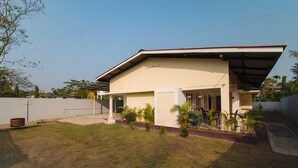 A modern two-story house with a flat roof, a covered porch, and a small garden with palm trees. - Royal Vista (Jorhat)