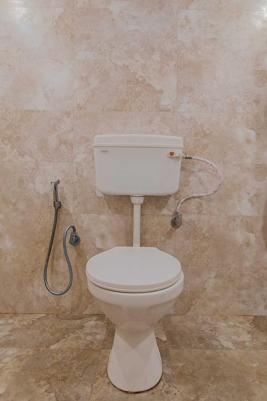 Un inodoro con tanque y un accesorio bidé, frente a una pared con azulejos.