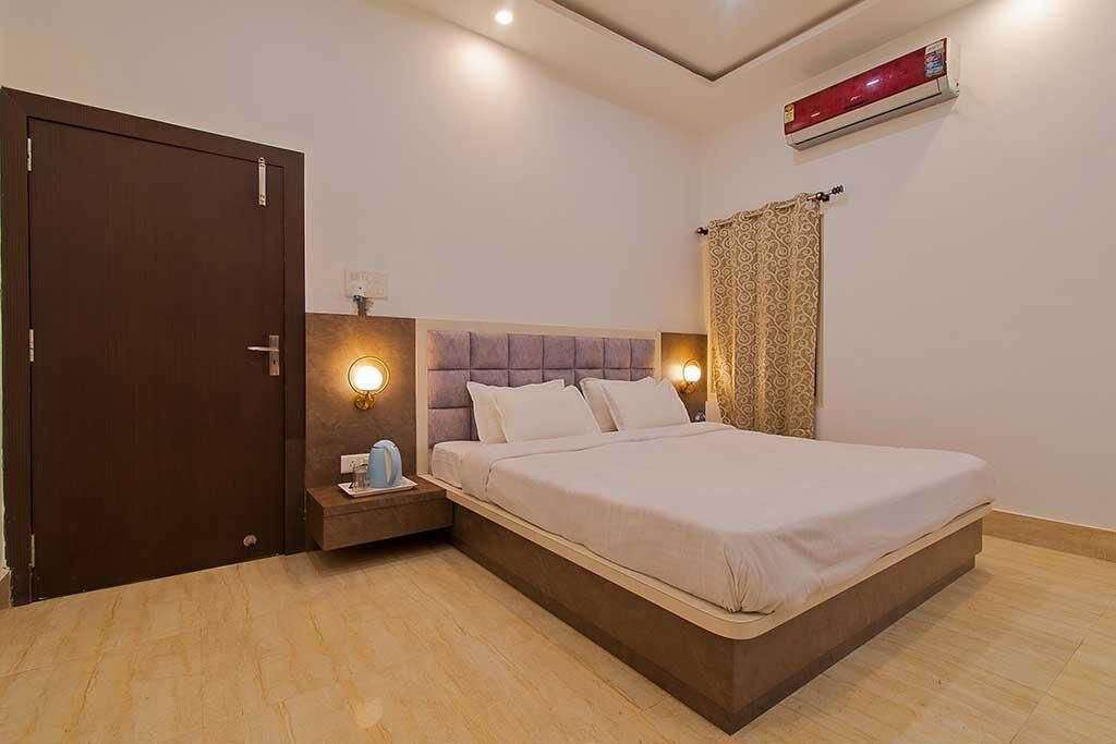 A bedroom with a bed, bedside table, and a wall-mounted air conditioner.