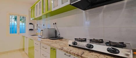 A modern kitchen with white cabinets, a granite countertop, a gas stove, and a microwave.