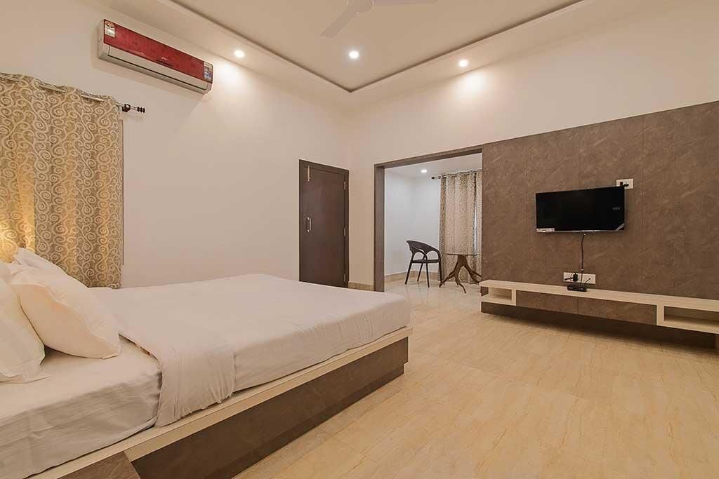 A modern bedroom with a bed, a TV mounted on the wall, and a ceiling fan.