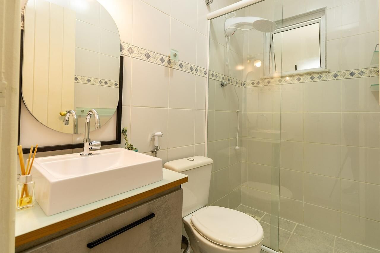 A bathroom with a white sink, a mirror, a toilet, and a glass-enclosed shower.