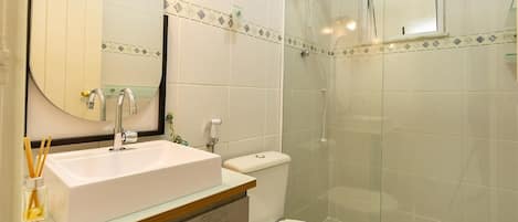 A bathroom with a white sink, a mirror, a toilet, and a glass-enclosed shower.