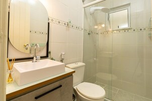 A bathroom with a white sink, a mirror, a toilet, and a glass-enclosed shower.