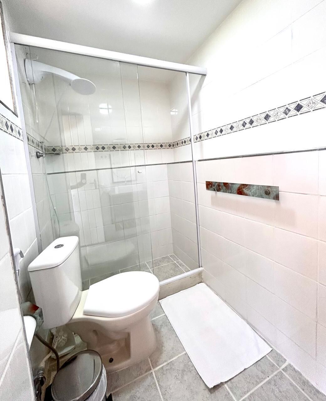 Ein kleines, modernes Badezimmer mit Duschkabine aus Glas, Toilette und Waschbecken.